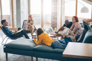 Group of young people spending their time in common living room. Checking their gadgets to catch up with latest news or messages. They are friends who sharing living space.