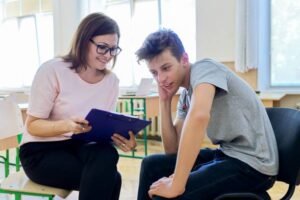 Woman school psychologist talking and helping student, male teenager. Mental health of adolescents, psychology, social issues, professional help of counselor