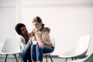 Young distraught woman being consoled by African American woman at community center. Copy space.