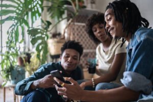 Young man showing something on the mobile phone to his friends at home