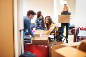 A group of three female university students move into their shared flat , and start to unpack boxes. One of the students is a wheelchair user and is chatting to her new friends as they unpack their boxes in a communal lounge .